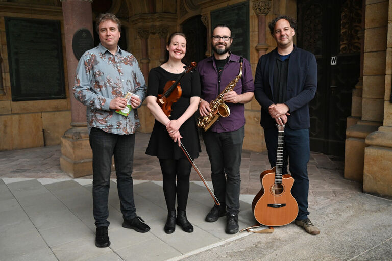 Gruppenbild des lächelnden Ensembles mit seinen Instrumenten