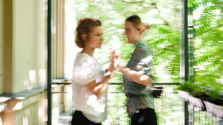 Verwackeltes Foto von zwei Frauen, die auf einem Balkon miteinander reden.