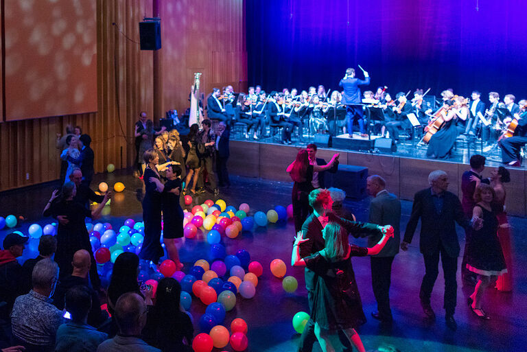 Viele Menschen feiern im Großen Saal der Hochschule, tanzen oder lauschen der Musik.