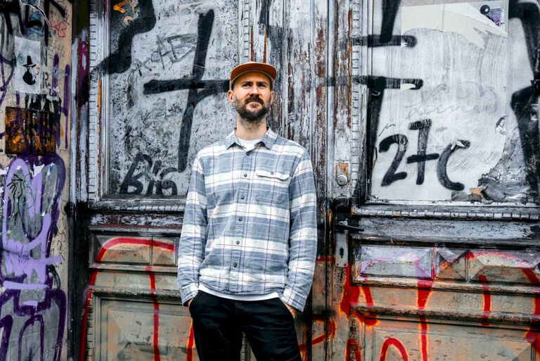 Foto des Musikers vor einem Tot, das mit Graffiti bedeckt ist