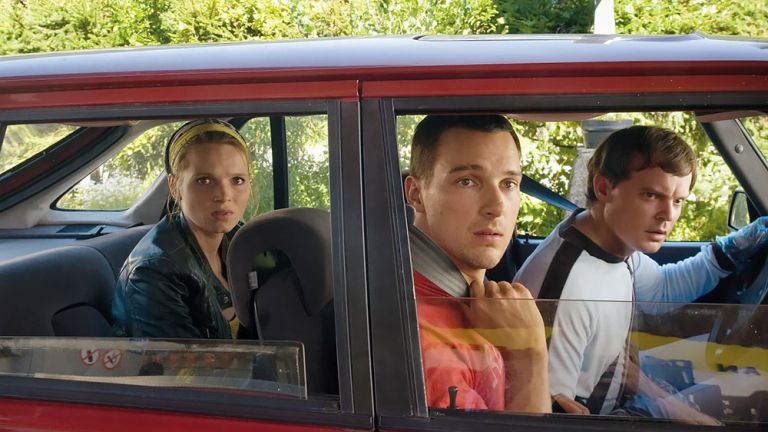 Filmszene, in der die drei Hauptfiguren in einem Auto sitzen und ganz verwundert nach außen schauen
