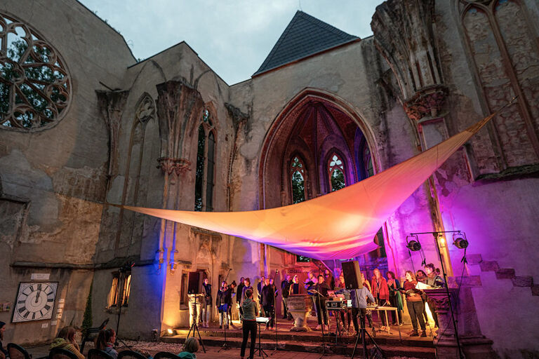 Ein Chor tritt in einer Kirchenruine auf