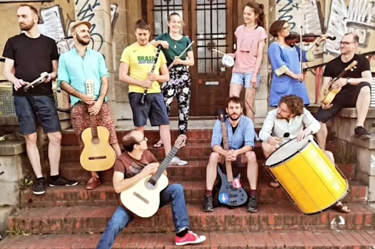 Gruppenfoto der sich unterhaltenden Musikerinnen und Musiker mit ihren Instrumenten auf einer Treppe