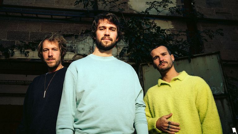 Gruppenfoto des Trios in einer verfallen Industriehalle