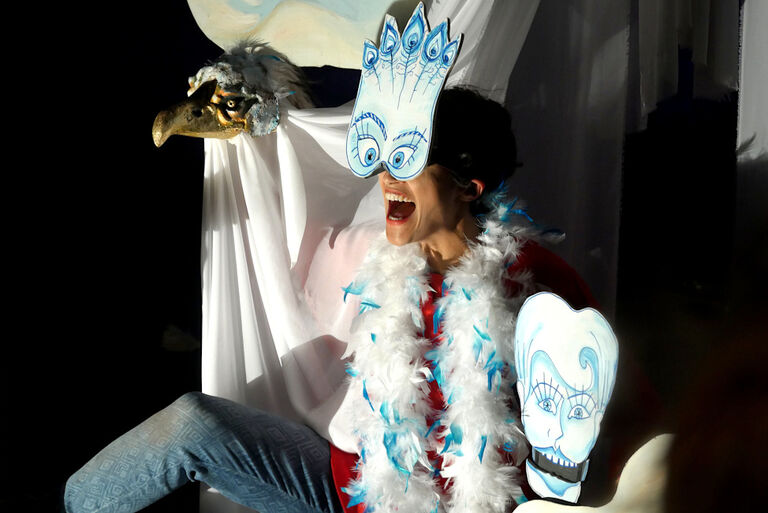 Eine lachende Schauspielerin mit einer weißen Maske und der Puppe eines Adlers