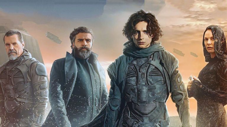 Filmszene mit vier Schauspieler*innen in futusistischen Kostümen in einer Wüste mit Flugobjekten am Himmel.