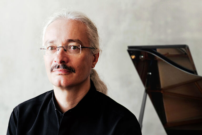 Porträt des ernst blickenden Musikers vor einem Konzertflügel
