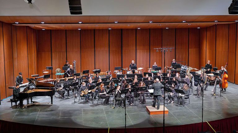 Das Orchester spielt in einem großen holzvertäfelten Saal.