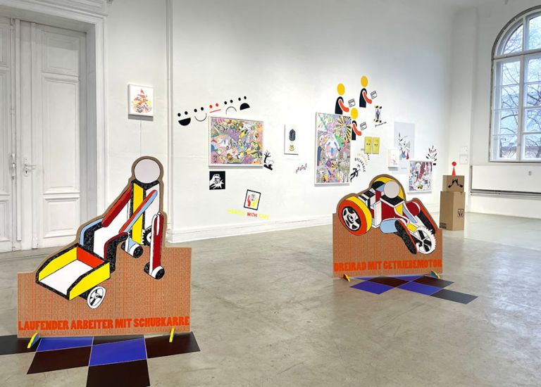 Blick in die Ausstellung mit Bildern an den Wänden und Skulpturen in einem hellen und großen Raum