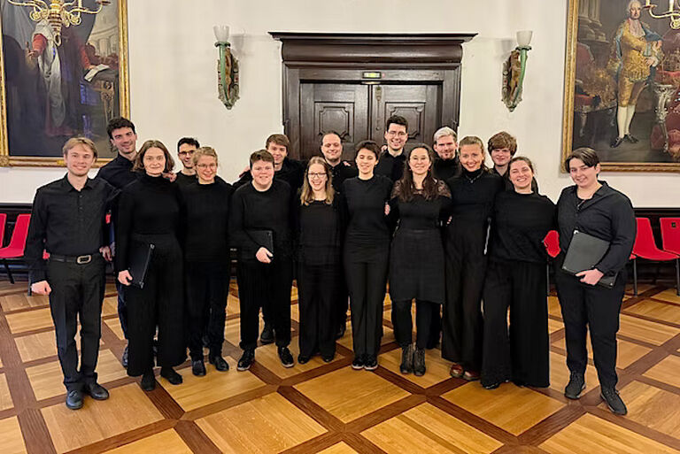 Gruppenfoto des Ensembles in einem historischen Saal mit Gemälden an den Wänden