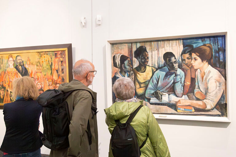 Besucher einer Ausstellung stehen vor zwei Gemälden