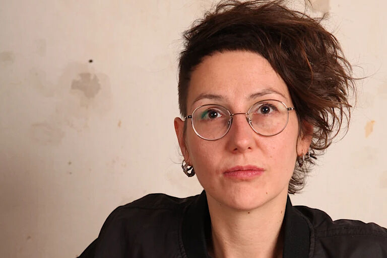 Portraitfoto von Jule Govrin mit Nickelbrille und hochgesteckten Haaren