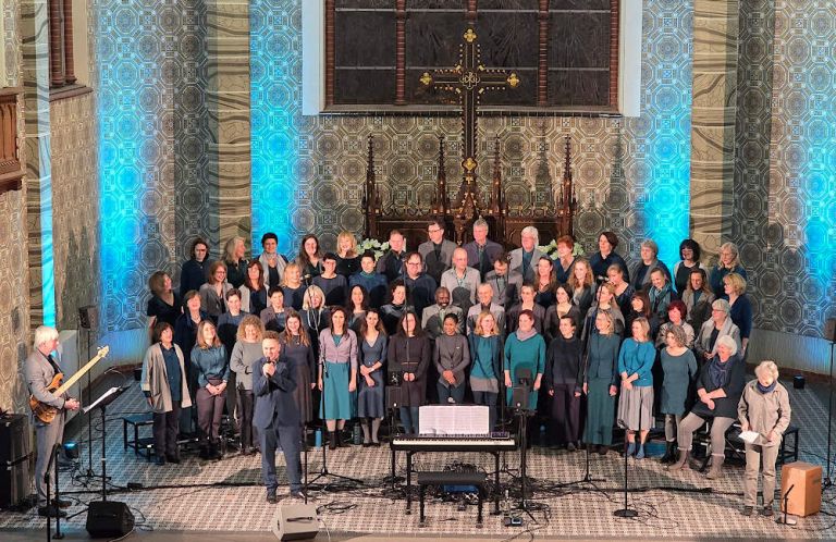 Der Chor bei einem Auftritt in der mit blauen Licht angestrhlten Kirche