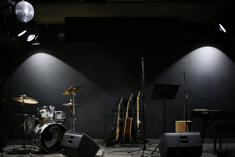 Foto der Bühne im Villakeller mit Schlagzeug, Gitarren, Mikrofonen und einem Keyboard
