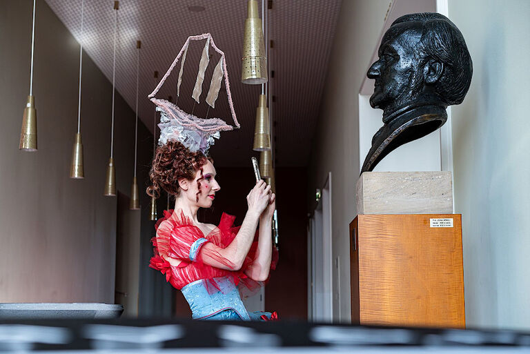 Eine junge Frau fotografiert eine Büste von Richard Wagner mit ihrem Smartphone.