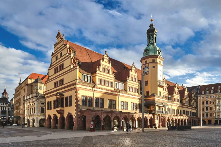 Die gelbe Fassade des Rathauses am Markt in Leipzig leuchtet im Sonnenschein.