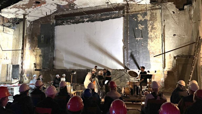 Konzert im notdürftig sanierten Kino der Jugend, bei dem die Band und das Publikum Bauhelme tragen