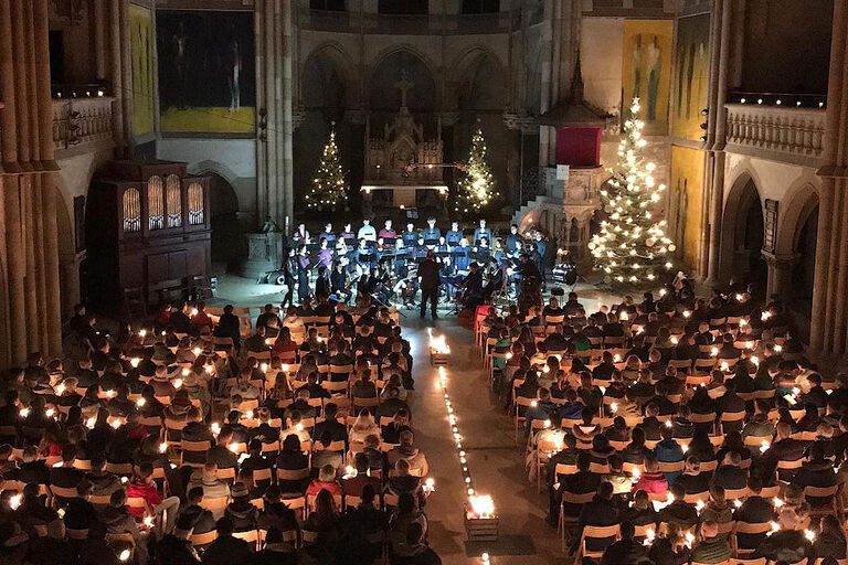 Foto aus der Peterskirche mit dicht besetzten Kirchenbänken und einem Chor im festlich erleuchteten Altarraum