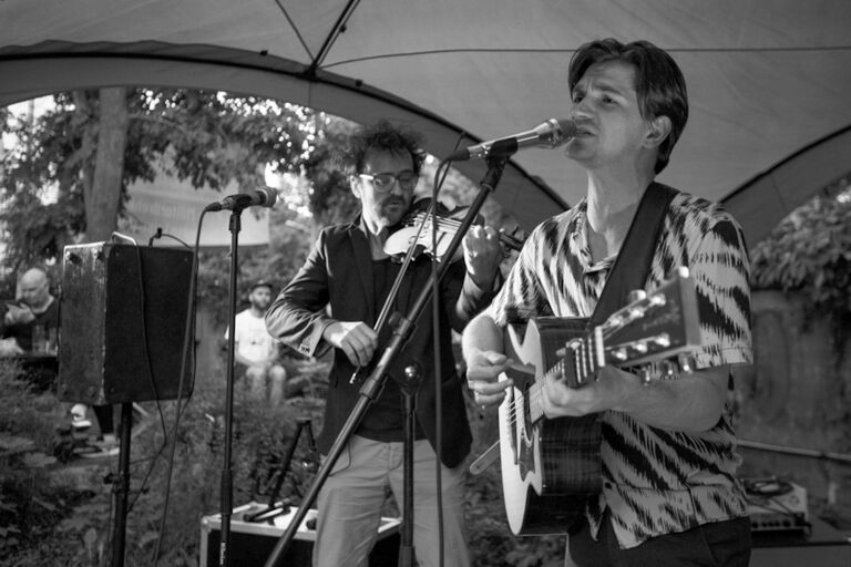 Das Duo beim Auftritt: Deen spielt Gitarre und singt, währen Blumenstein Geige spielt.