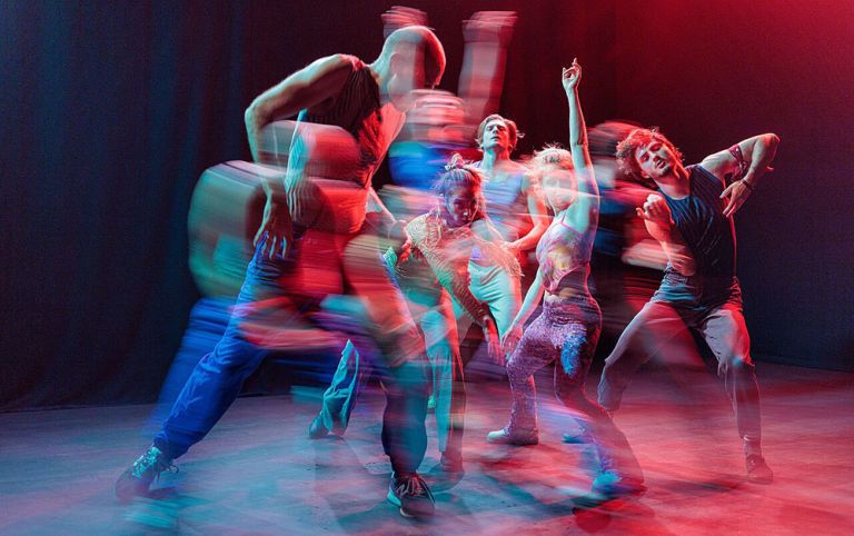 Foto einer Tanzperformance, bei dem die Dynamik der Tänzerinnen und Tänzer durch Bewegungsunschärfe unterstrichen wird.