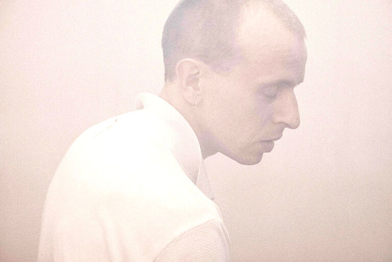 Portraitfoto des Musikers mit geschlossenen Augen und entspanntem Gesichtausdruck in heller Pastellfarbe