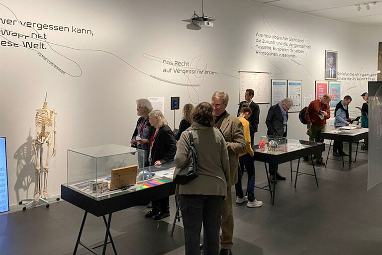 Blick in den Ausstellungsraum, in dem sich einige Besucher Exponate in Glasvitrinen ansehen