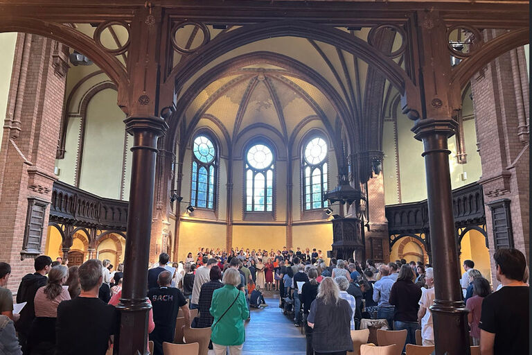 In einer Kirche singen viele Menschen stehend bei einem Chorchonzert mit
