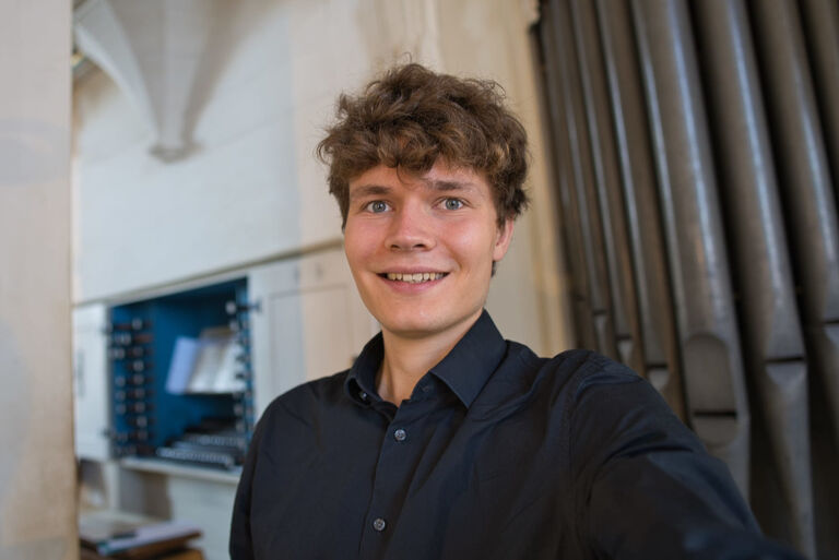Selfie des lächelnden Musikers vor einer Orgel