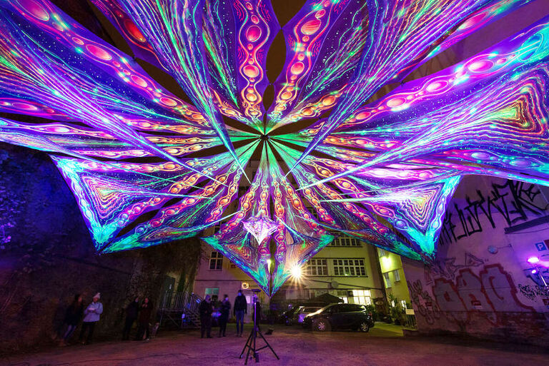 Eine große sternförmige Lichtinstallation über einem kleinen Platz