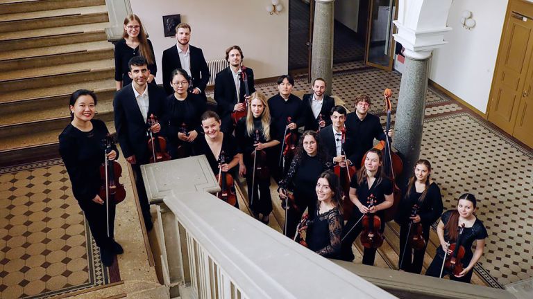 Gruppenfoto der jungen Musikerinnen und Musiker mit ihren Instrumenten in einem schönen alten Treppenhaus