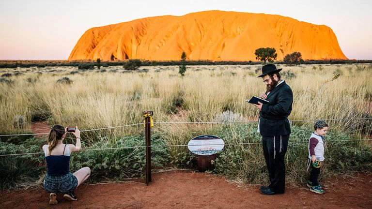 Ein orthodoxer Rabbi mit seiner jungen Familie in Australien vor dem Hintergrund des Ayers Rock.