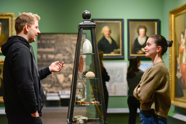 Ein Mann und eine Frau unterhalten sich vor einer Vitrine in der Ausstellung des Alten Rathauses von Leipzig.