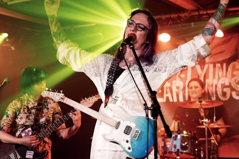 Foto der Band bei einem Konzert auf einer kleien Bühne und grünen Lichteffekten