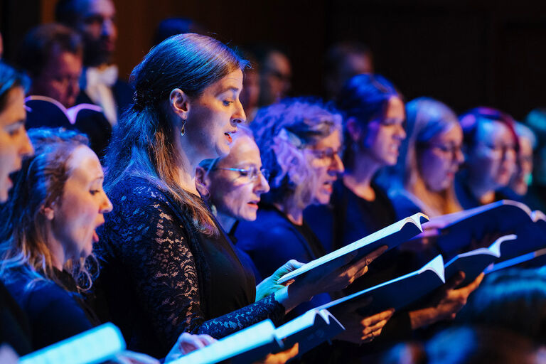 Nahaufnahme von Sängerinnen des GewandhausChores mit ihren Notenmappen in der Hand bei einem Konzert