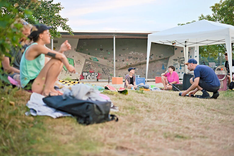 Mehrere Personen sitzen auf einer Wiese und lauschen einem Live-Hörspiel