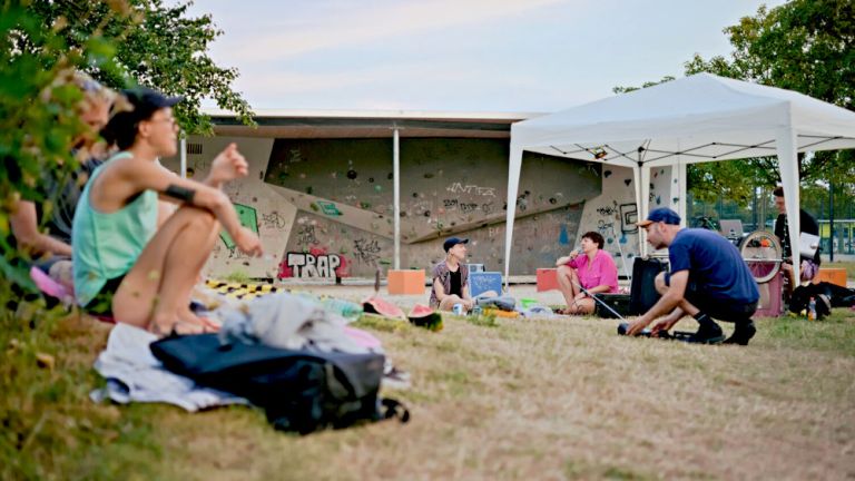 Mehrere Personen sitzen auf einer Wiese und lauschen einem Live-Hörspiel