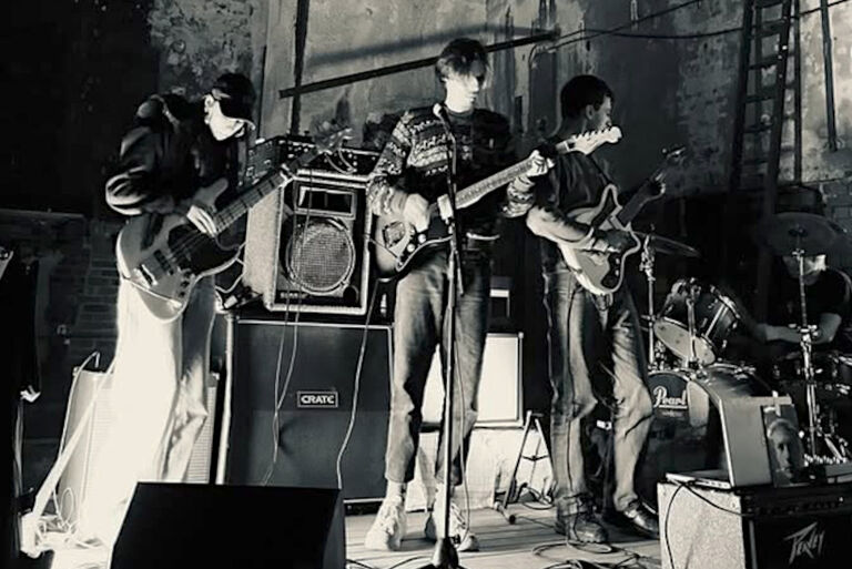 Düsteres Schwarz-Weiß-Foto der Band bei einem Konzert in einer verfallenen Halle