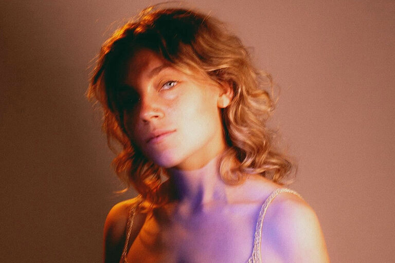 Verträumtes Porträtfoto der Musikerin, auf dem die Hälfte ihres Gesichts im Schatten liegt