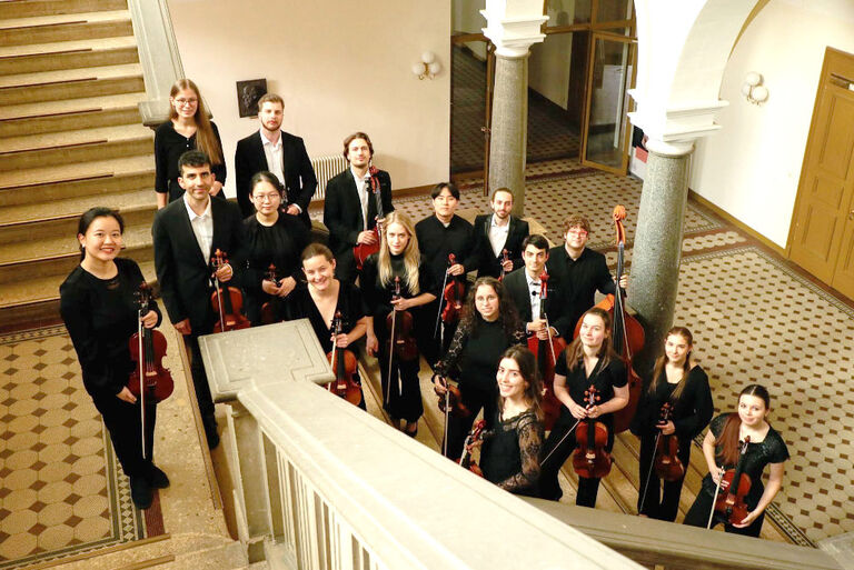 Gruppenfoto der jungen Musikerinnen und Musiker mit ihren Instrumenten in einem schönen alten Treppenhaus
