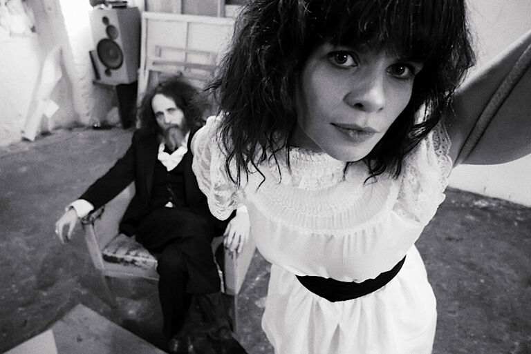 Schwarz-Weiß-Foto des Duos, auf dem das Gesicht der Frau nah im Vordergrund zu sehen ist und sich dem Mann im Hintergrund befindet