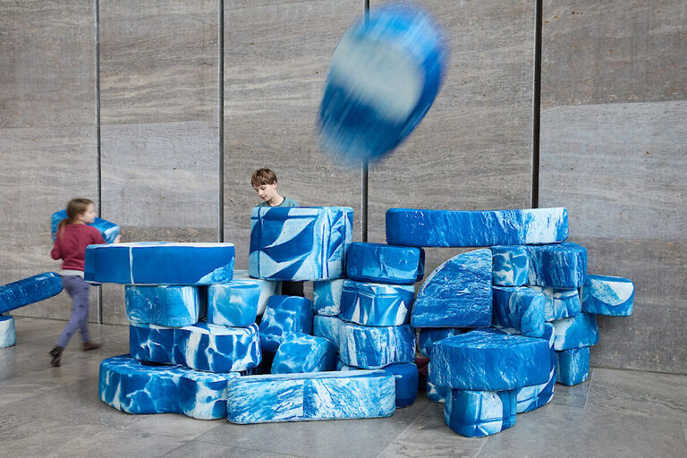 Zwei Kinder spielen mit den weiß-blauen Elementen des Kunstwerks