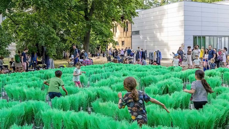 Foto eines Flohmarktes an der Galerie. Im Vordergrund laufen Kinder durch ein Labyrinth aus knstlichen Pflanzen.
