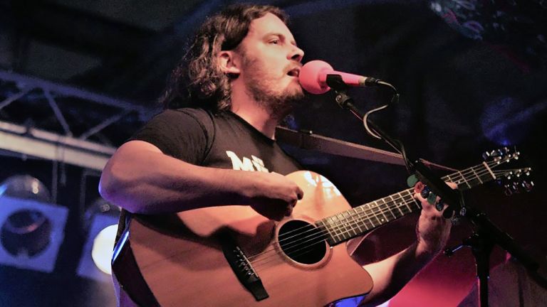 Der Musiker bei einem Konzert mit Gitarre und vor einem Mikrofon
