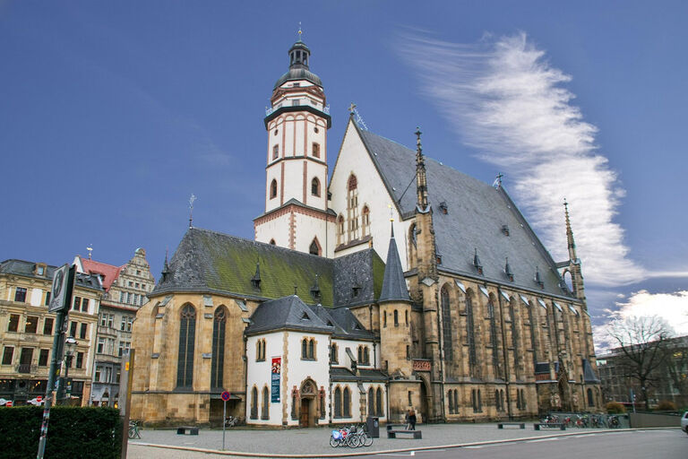 Ansicht der Thomaskirche in Leipzig vor blauem Himmel mit weißen Wolken