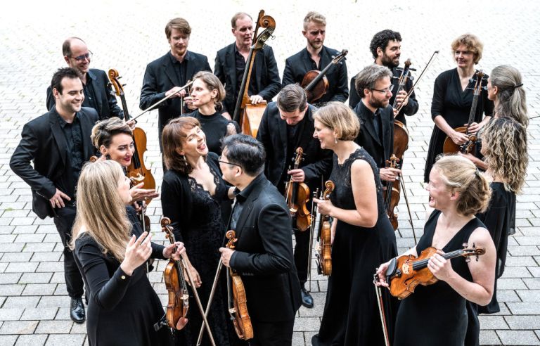Die vier Musikerinnen und Musiker stehen mit ihren Instrumenten auf einem Platz und unterhalten sich angeregt.