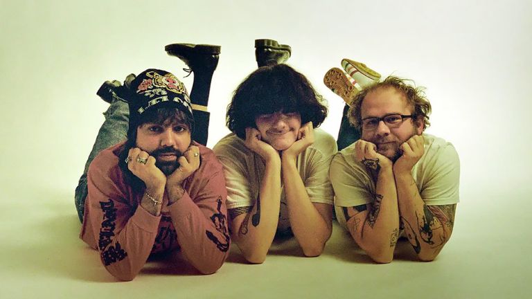 Gruppenfoto der drei auf dem Bauch liegenden Musiker