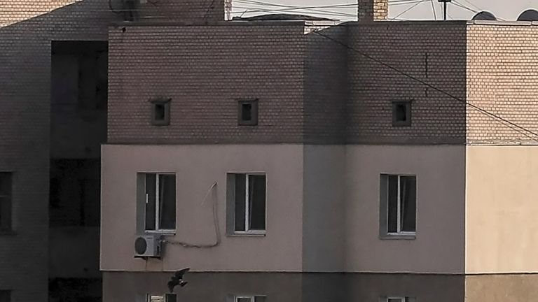 Die kahle Fassade aus gemauerten und teilweise verputzten Wänden wird von der Sonne beschienen.