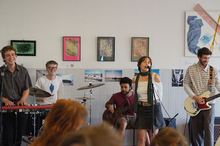 Vor einer Wand mit Fotos und Gemälden tritt eine Band auf.
