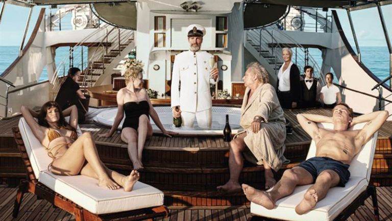 Passagier auf einer Luxusyacht liegen in Liegestühlen oder sitzen auf dem Poolrand, während der Kapitän bis zu den Knien im Wasser steht