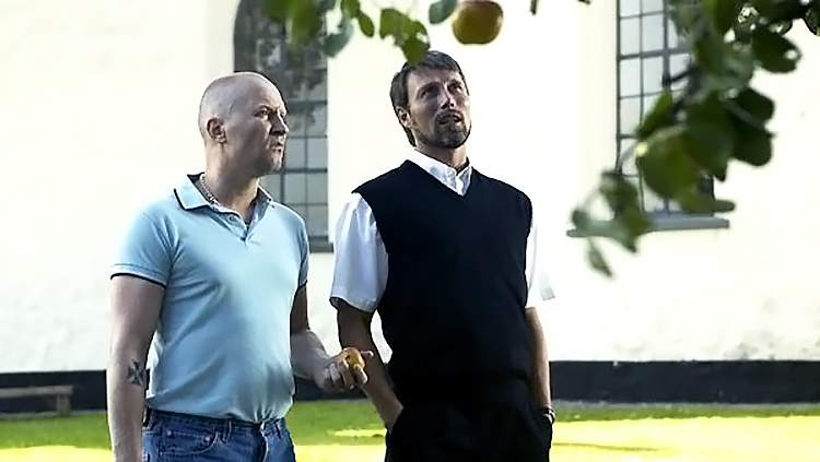 Adam und Pfarrer Ivan stehen vor einem Apfelbaum und unterhalten sich.